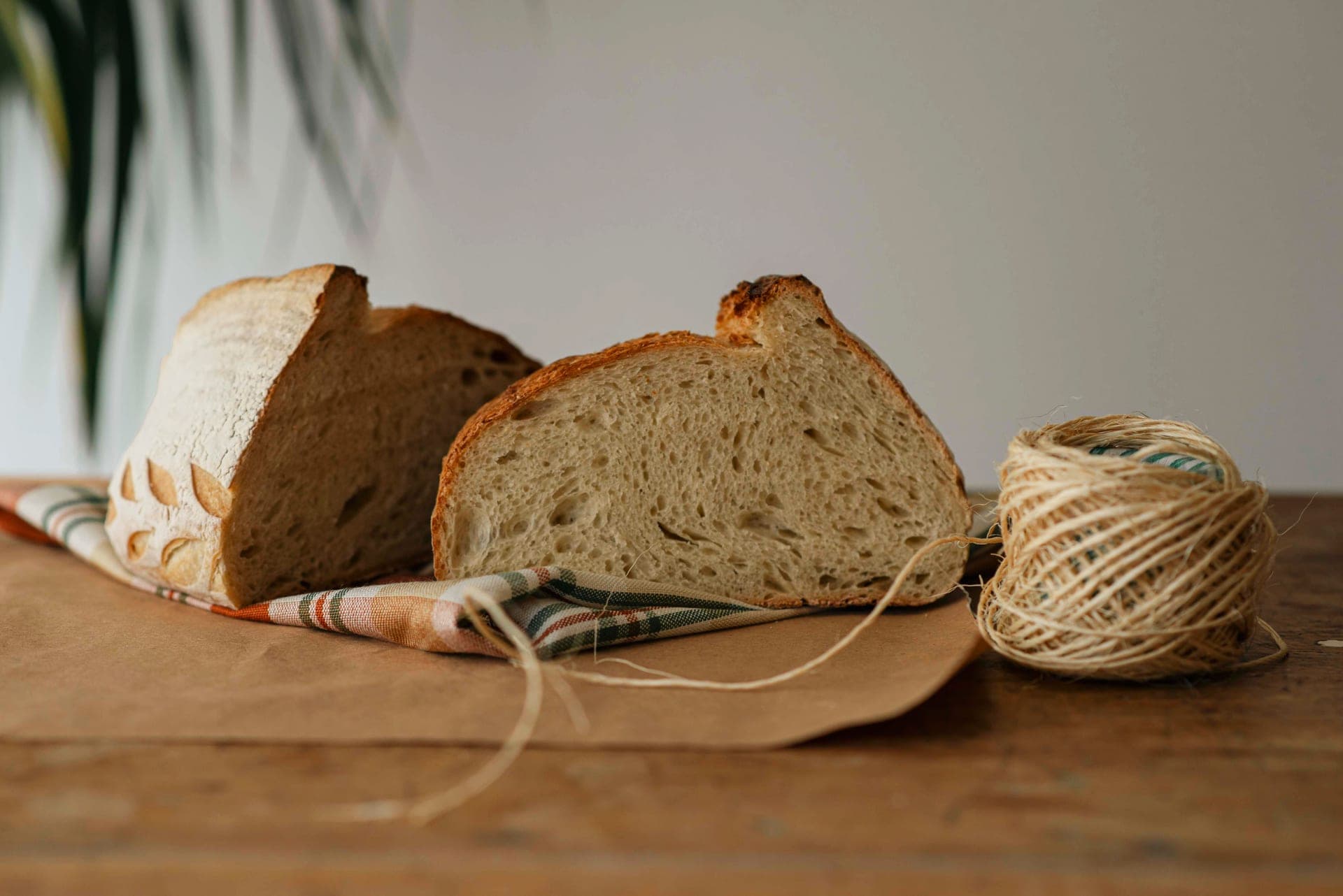 Sliced artisan loaf on a cloth with twine on a wooden table
