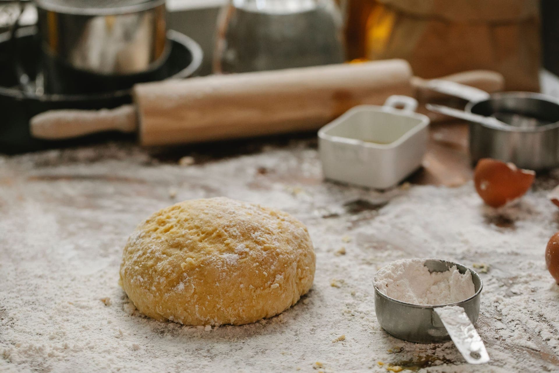 Dough, a rolling pin and baking tools on a floured table