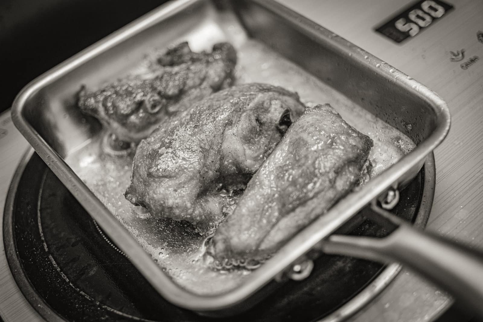 Food cooking in a dark steel frying pan