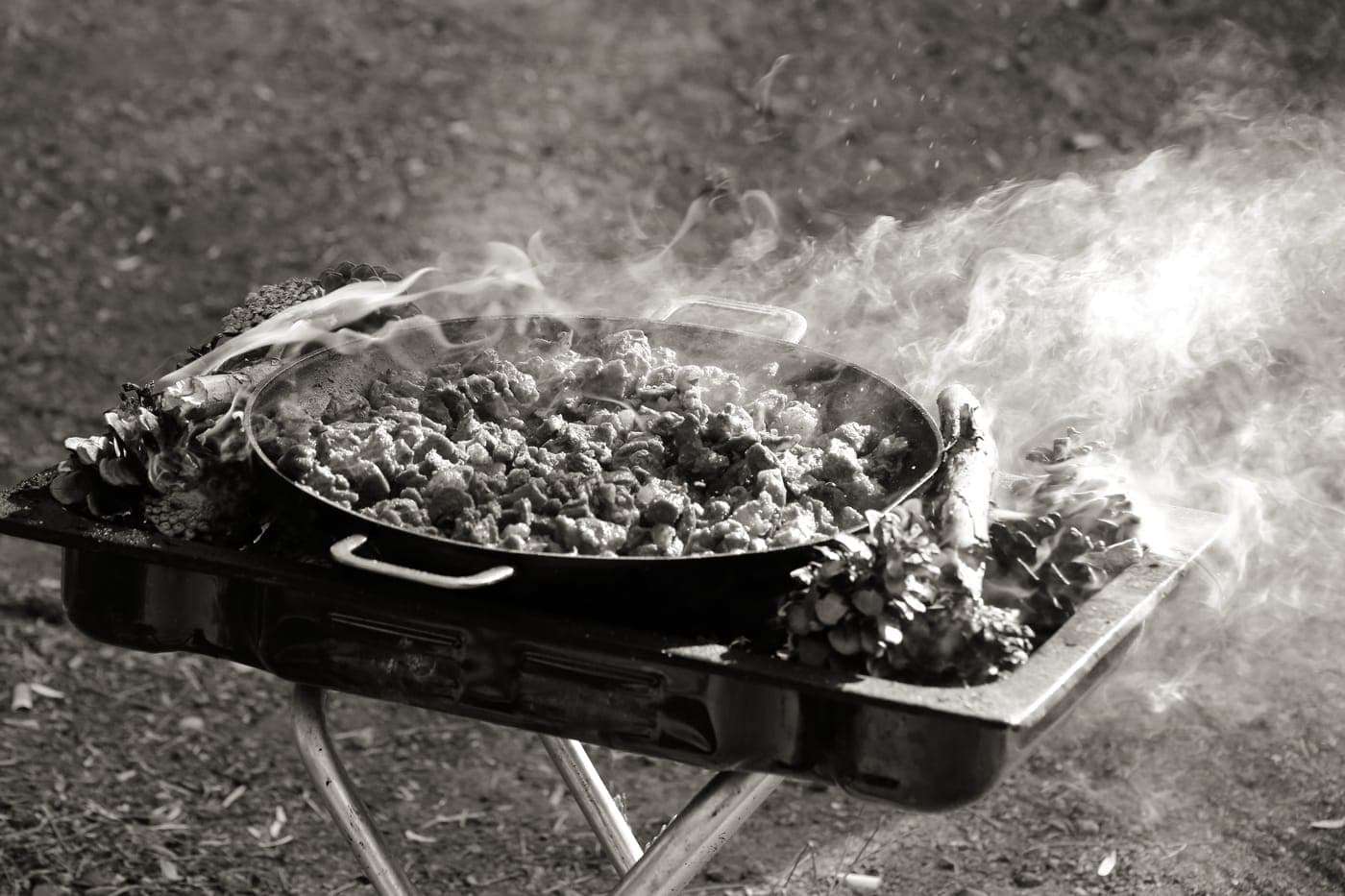 A pan being seasoned over a flame with oil just beginning to smoke