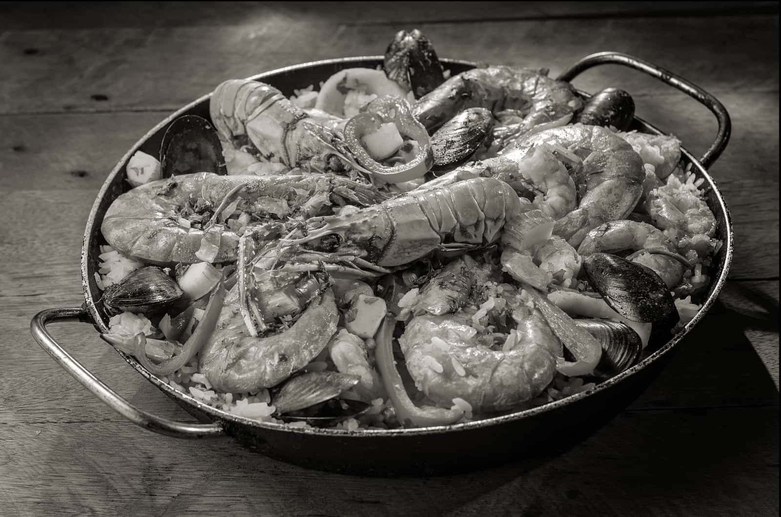 A wide shallow pan filled with rice and seafood