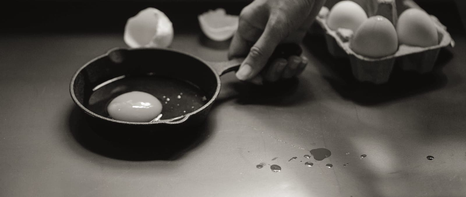 A cast iron skillet beside a white ceramic frying pan