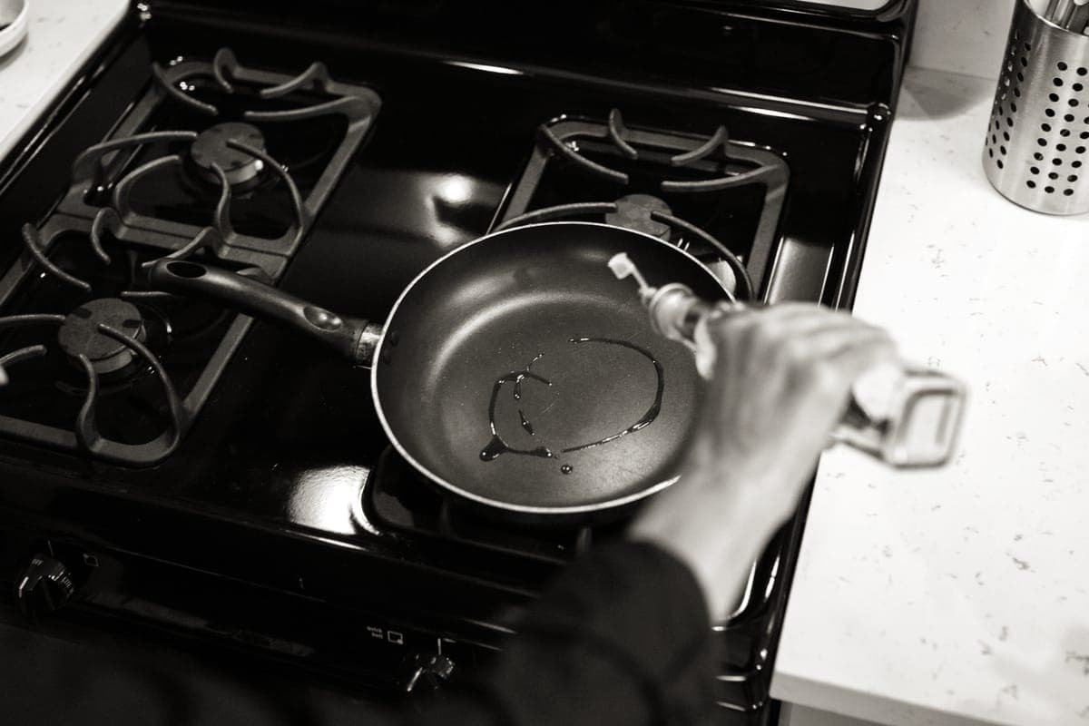 A thin film of oil being poured into a hot pan