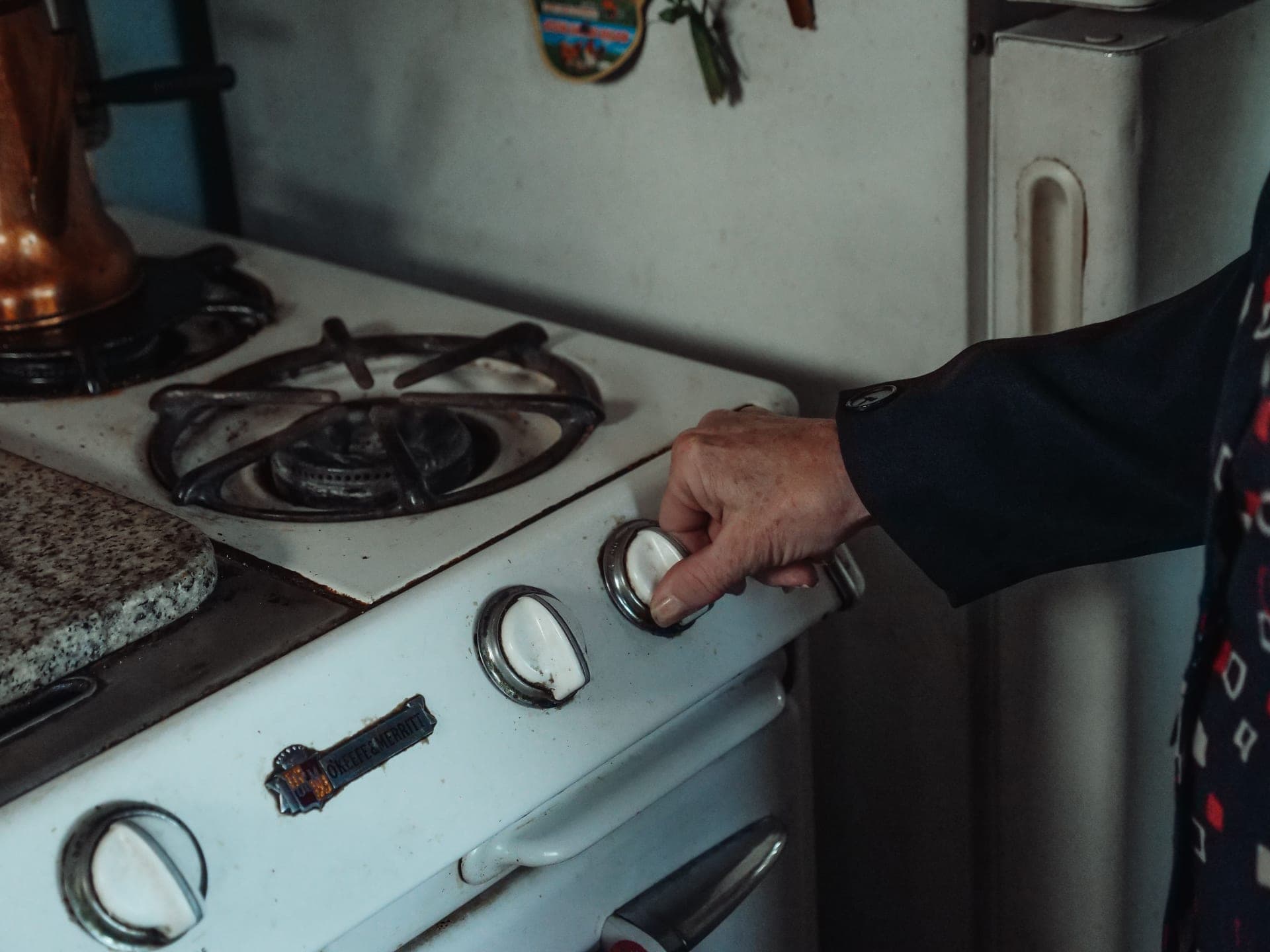 A hand turning the control knob on a kitchen stove