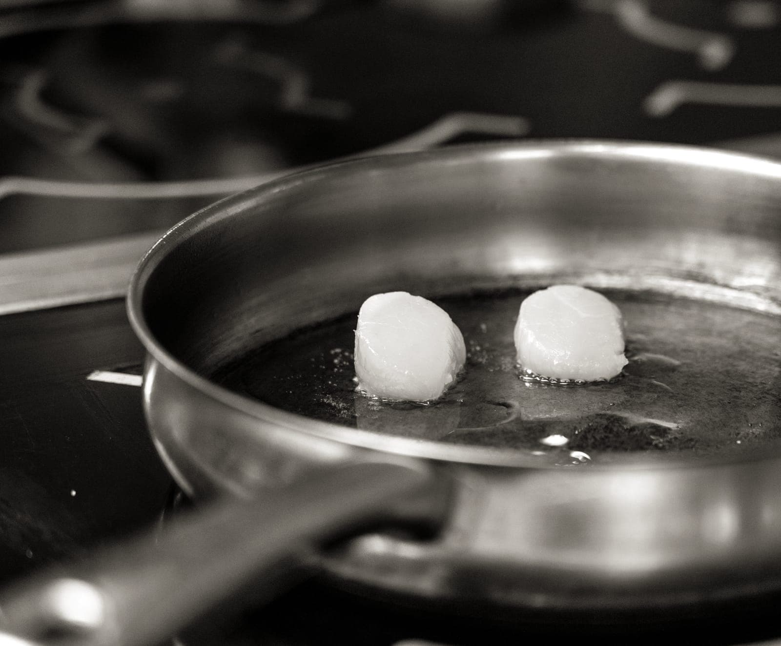 A dark carbon steel frying pan searing food over a flame