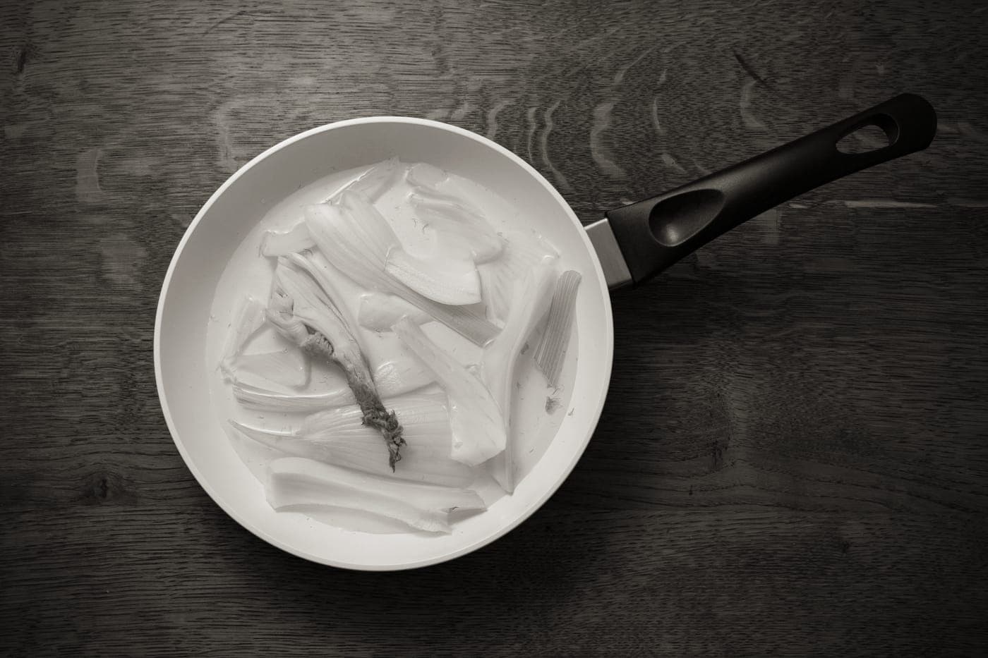 A white ceramic pan with vegetables cooking in it