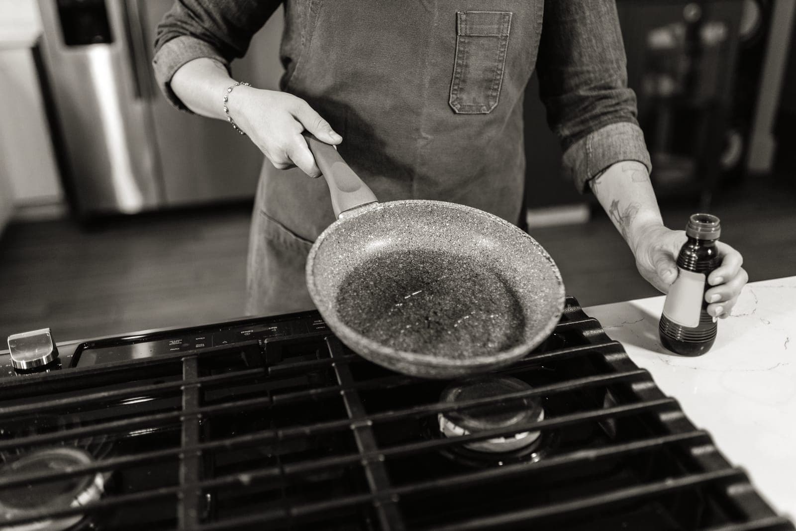 Oil being wiped around a frying pan with a paper towel