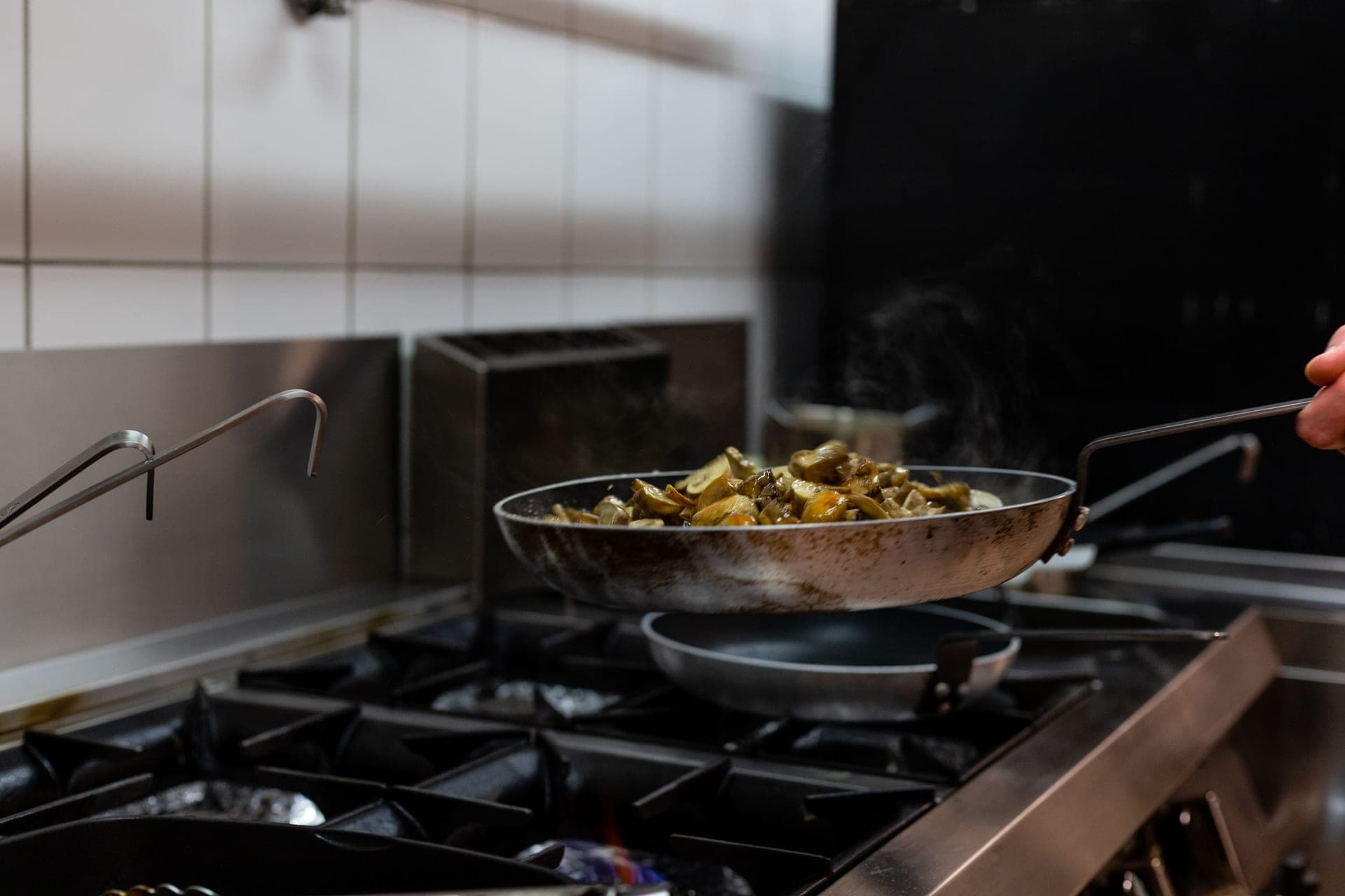 Mushrooms cooking in a wide stainless pan on a stovetop