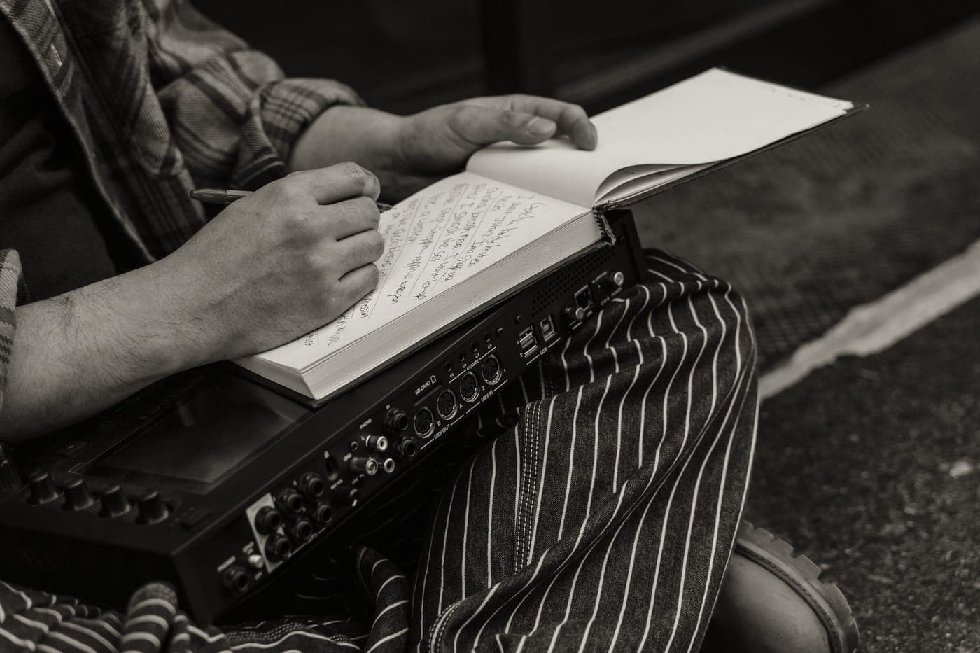Hands making notes beside cooking equipment on a work surface