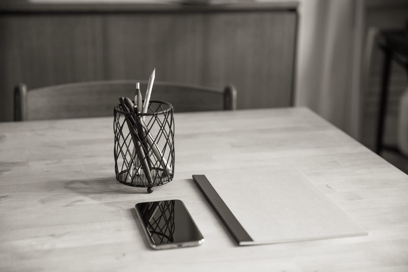 A plain kitchen table with a notebook and a pen
